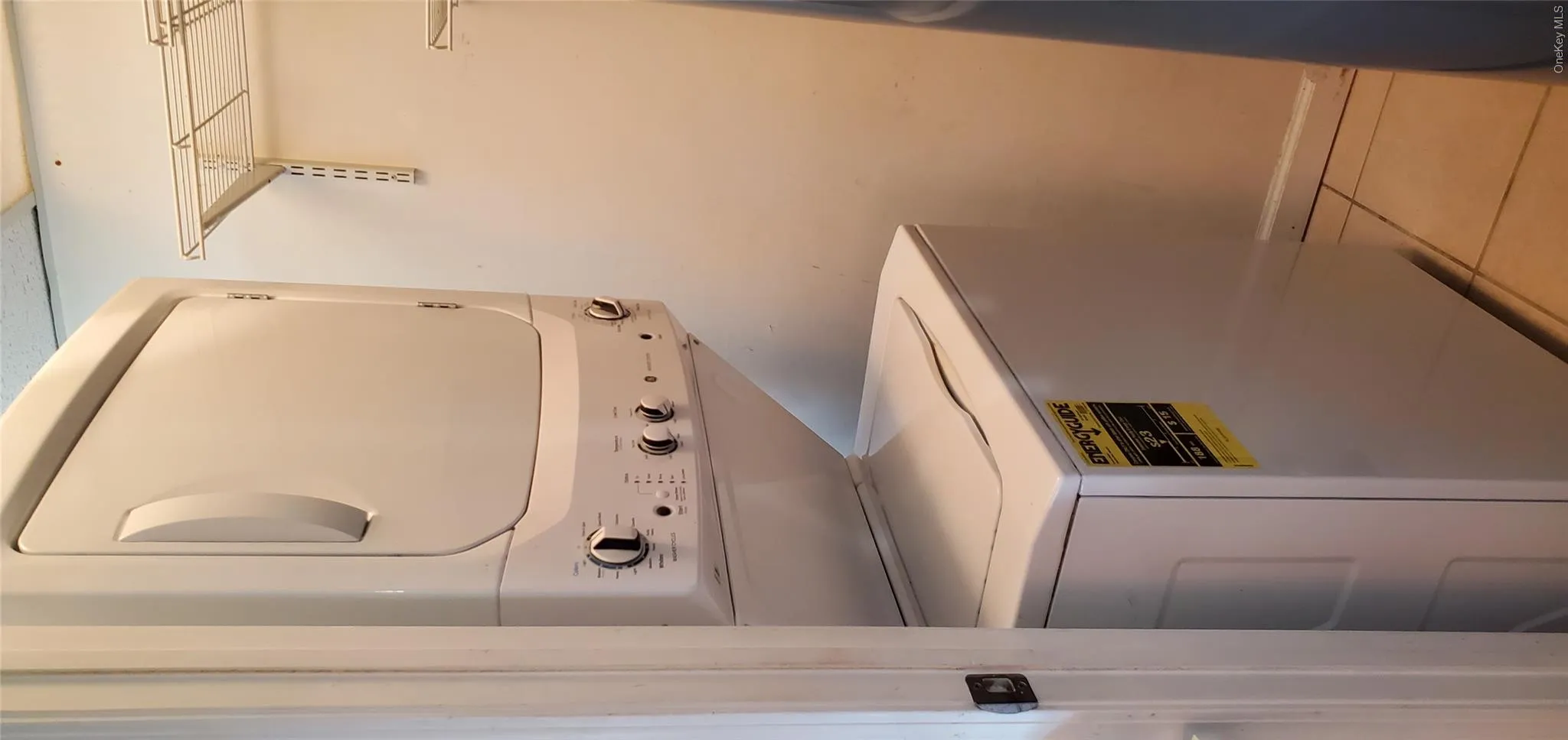 Clothes washing area with light tile patterned floors and stacked washer and dryer Clothes washing area with light tile patterned floors and stacked washer and dryer