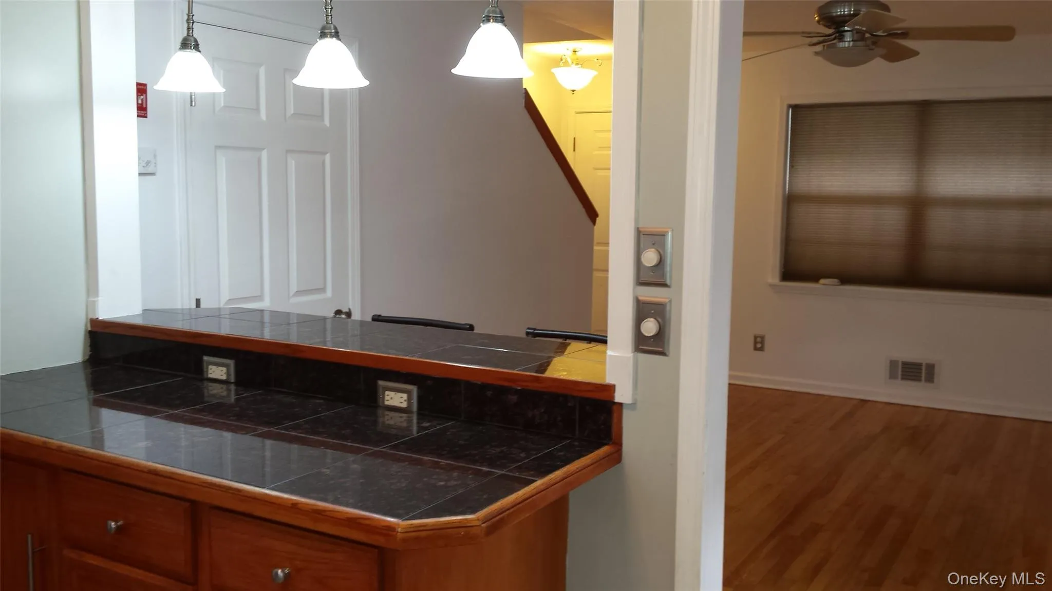 Kitchen featuring tile countertops, ceiling fan, hardwood / wood-style floors, and pendant lighting Kitchen featuring tile countertops, ceiling fan, hardwood / wood-style floors, and pendant lighting