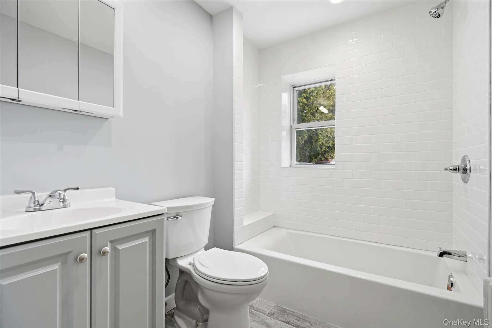 Renovated Full bathroom featuring vanity, bathtub / shower combination, and light wood-type flooring Renovated Full bathroom featuring vanity, bathtub / shower combination, and light wood-type flooring