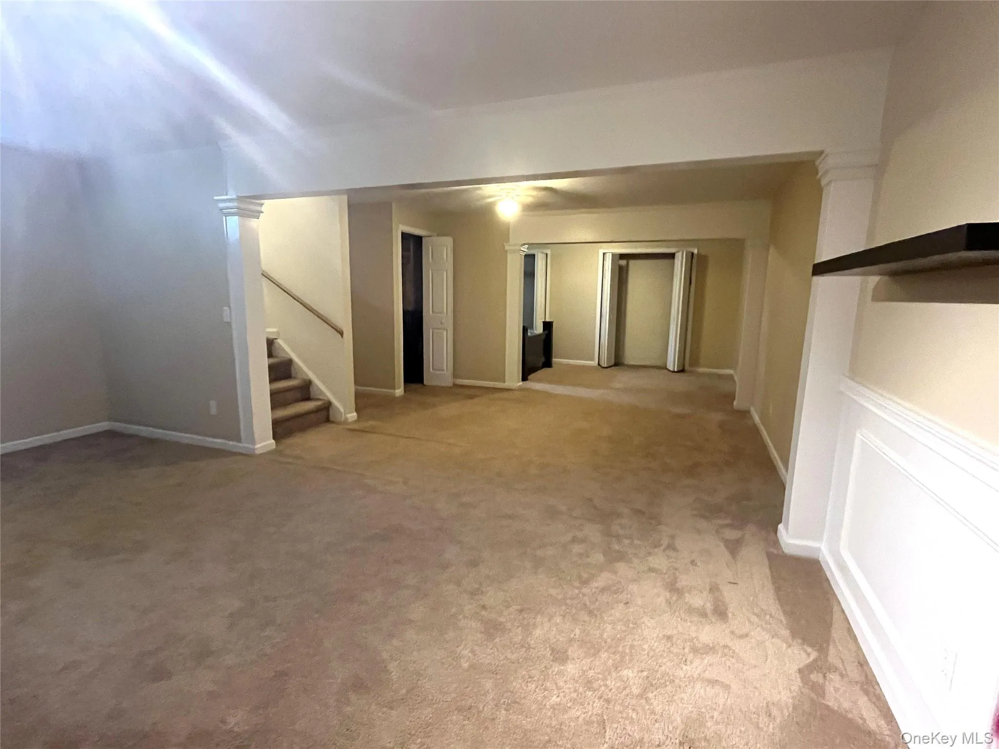 Spare room featuring light colored carpet and stairway Spare room featuring light colored carpet and stairway