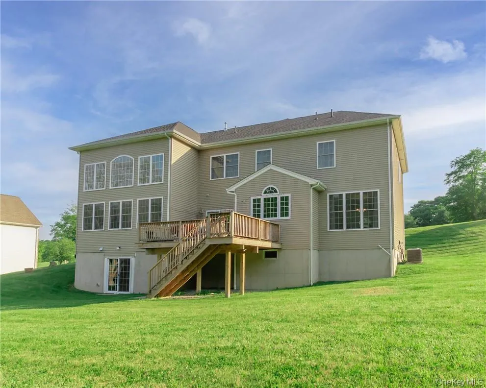 Back of house with a deck and a lawn Back of house with a deck and a lawn