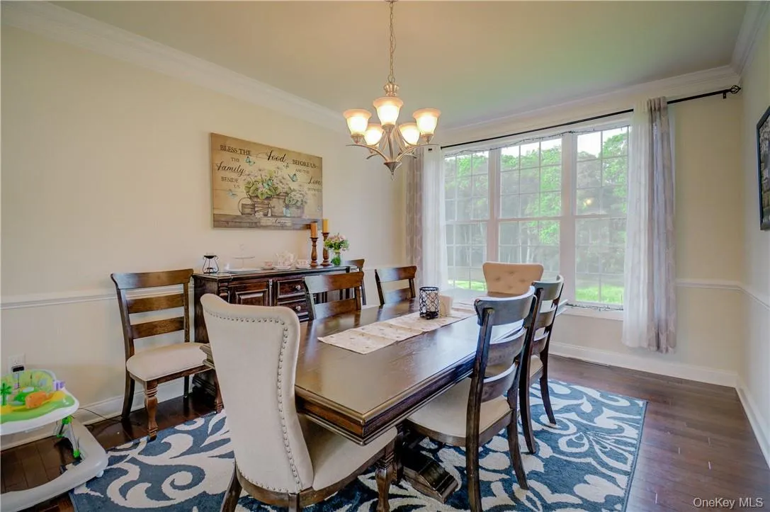 Dining area featuring dark hardwood / wood-style flooring, crown molding, and a chandelier Dining area featuring dark hardwood / wood-style flooring, crown molding, and a chandelier