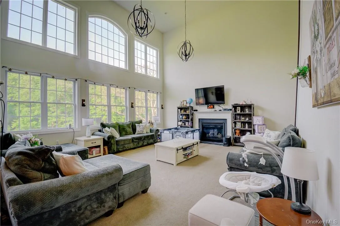 Carpeted living room featuring a notable chandelier and a towering ceiling Carpeted living room featuring a notable chandelier and a towering ceiling
