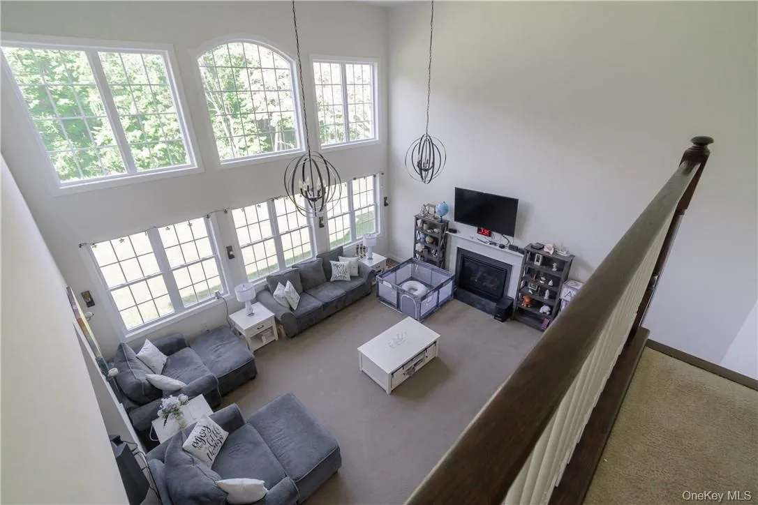 Carpeted living room with a high ceiling and a notable chandelier Carpeted living room with a high ceiling and a notable chandelier