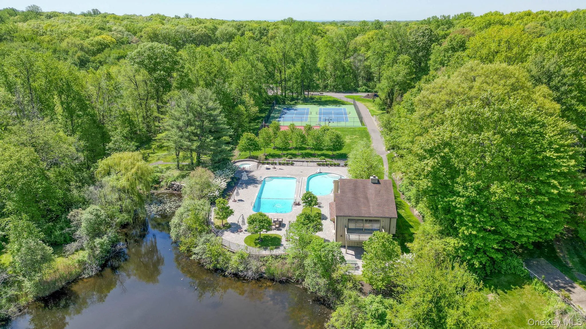 Drone view of the community pool and tennis courts and pond Drone view of the community pool and tennis courts and pond