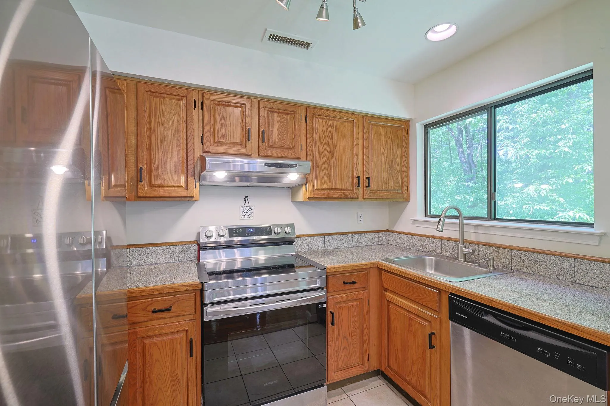 Kitchen featuring stainless steel appliances, natural light and wood cabinets Kitchen featuring stainless steel appliances, natural light and wood cabinets