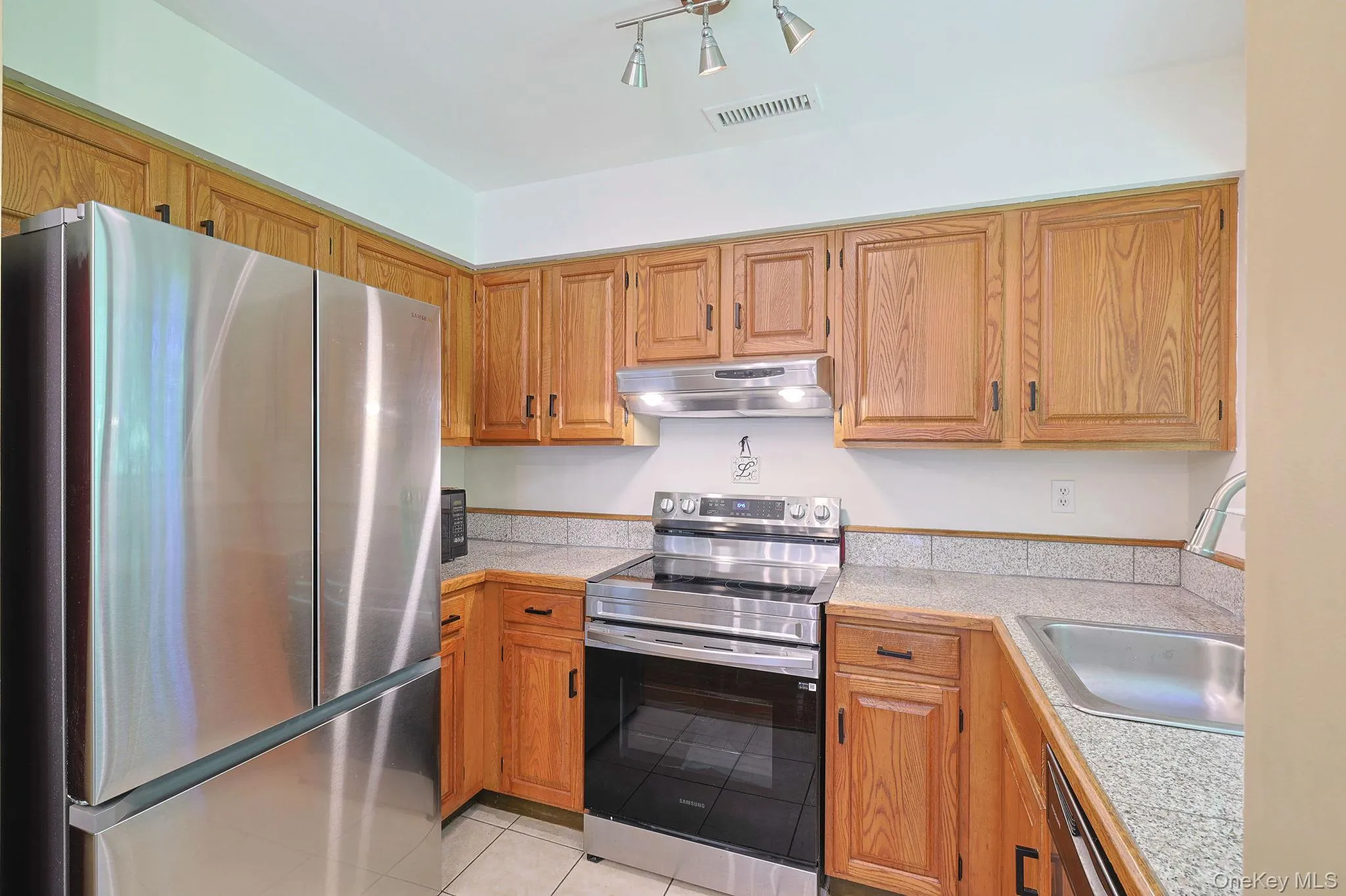 Kitchen featuring stainless steel appliances, natural light and wood cabinets Kitchen featuring stainless steel appliances, natural light and wood cabinets