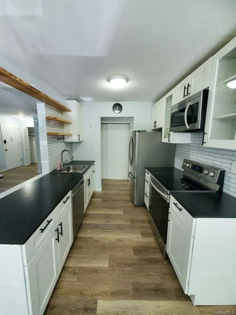 Kitchen featuring sink, white cabinetry, stove, and tasteful backsplash Kitchen featuring sink, white cabinetry, stove, and tasteful backsplash