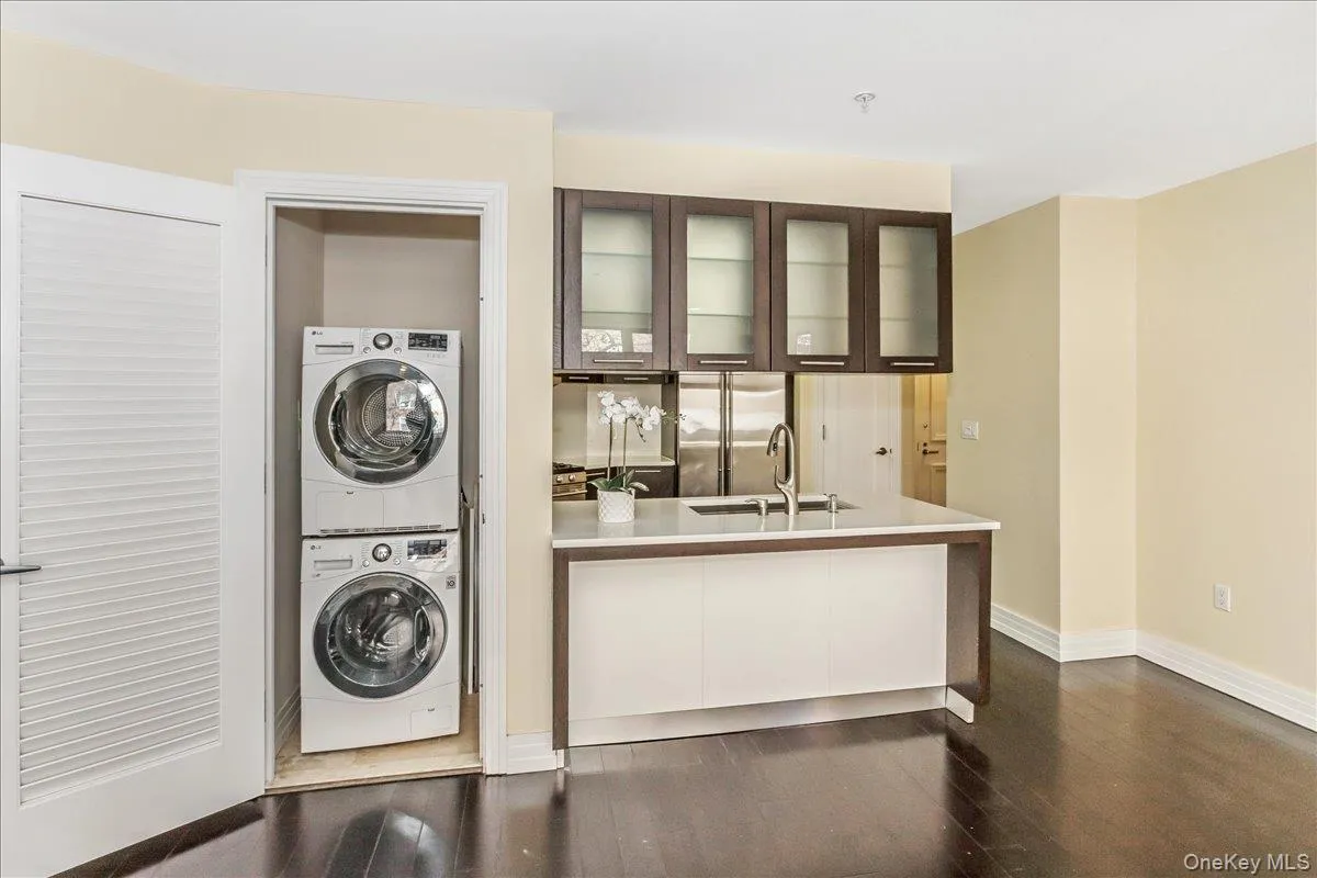 Laundry area featuring dark wood-style flooring and stacked washer and clothes dryer Laundry area featuring dark wood-style flooring and stacked washer and clothes dryer