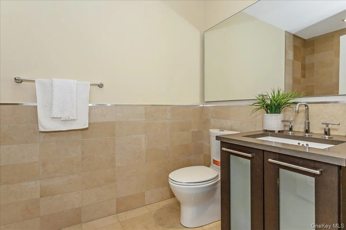 Full bathroom with tile walls, vanity, and light tile patterned floors Full bathroom with tile walls, vanity, and light tile patterned floors