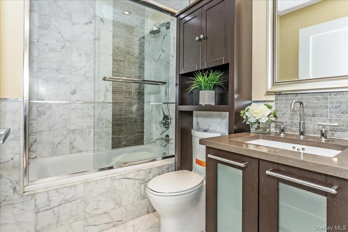 Full bath featuring vanity, backsplash, and bath / shower combo with glass door Full bath featuring vanity, backsplash, and bath / shower combo with glass door
