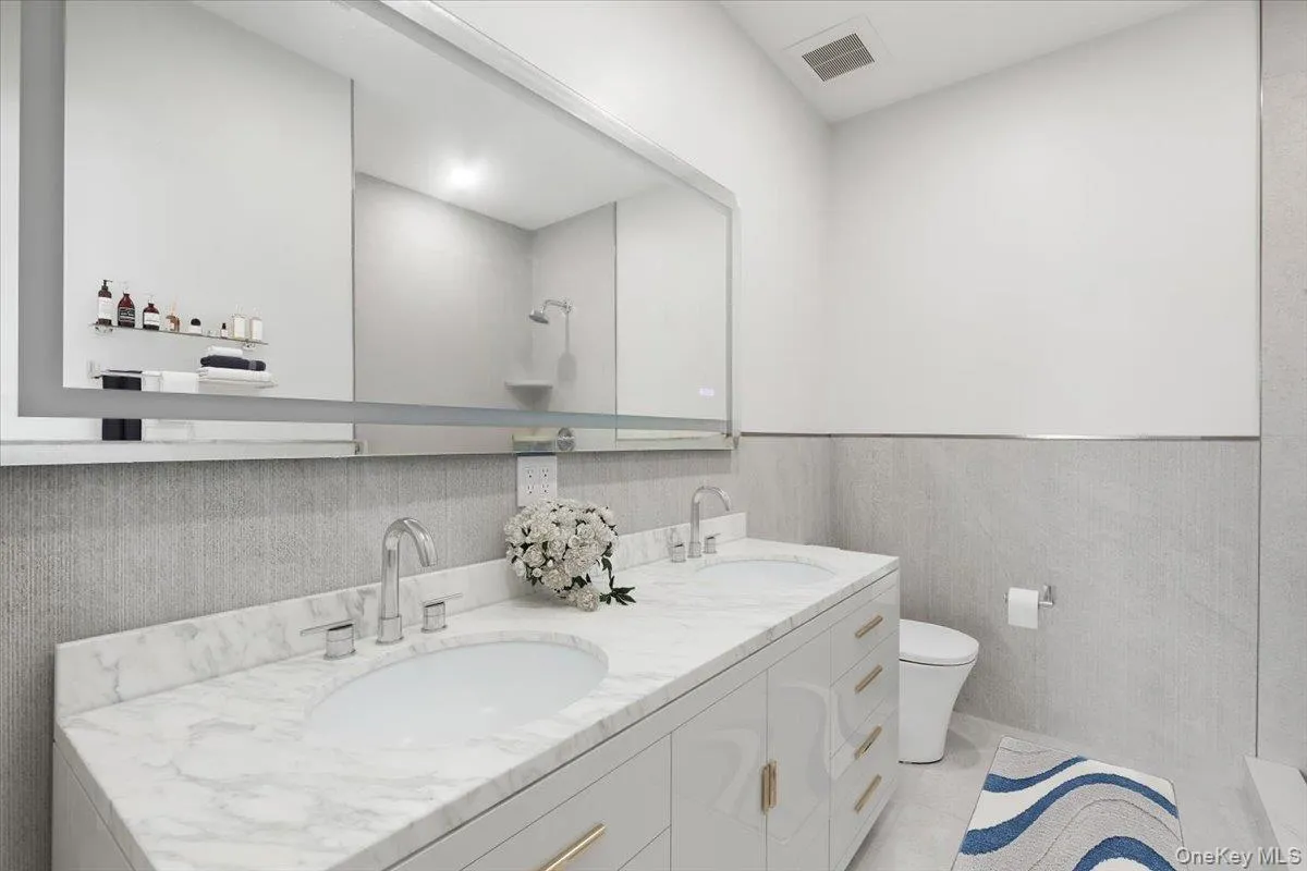 Full bath with double vanity and backlit mirror. Digitally staged. Full bath with double vanity and backlit mirror. Digitally staged.