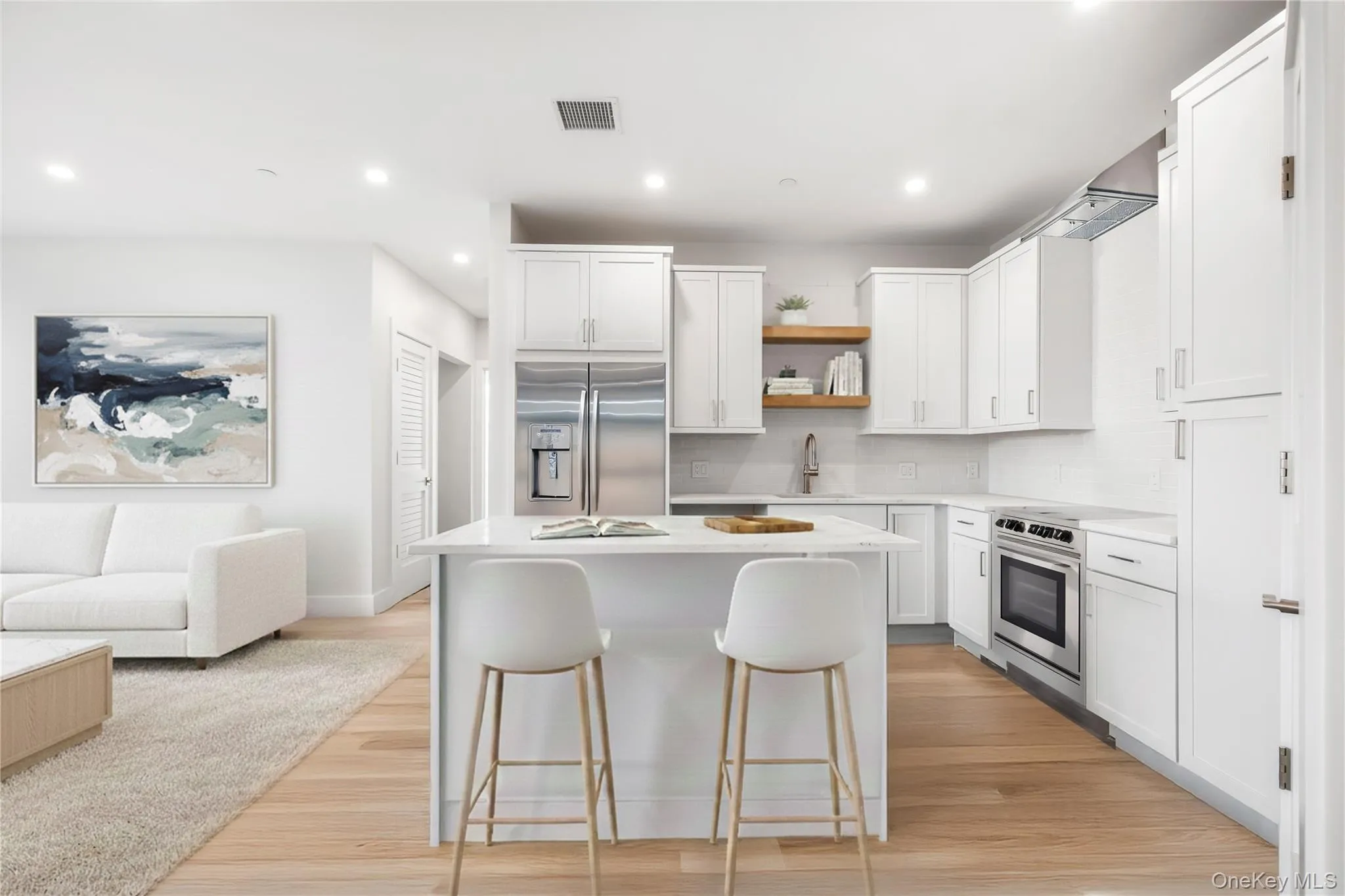 Kitchen featuring white cabinets, a kitchen island, stainless steel appliances, and recessed lighting. Open floor plan. Digitally staged. Kitchen featuring white cabinets, a kitchen island, stainless steel appliances, and recessed lighting. Open floor plan. Digitally staged.