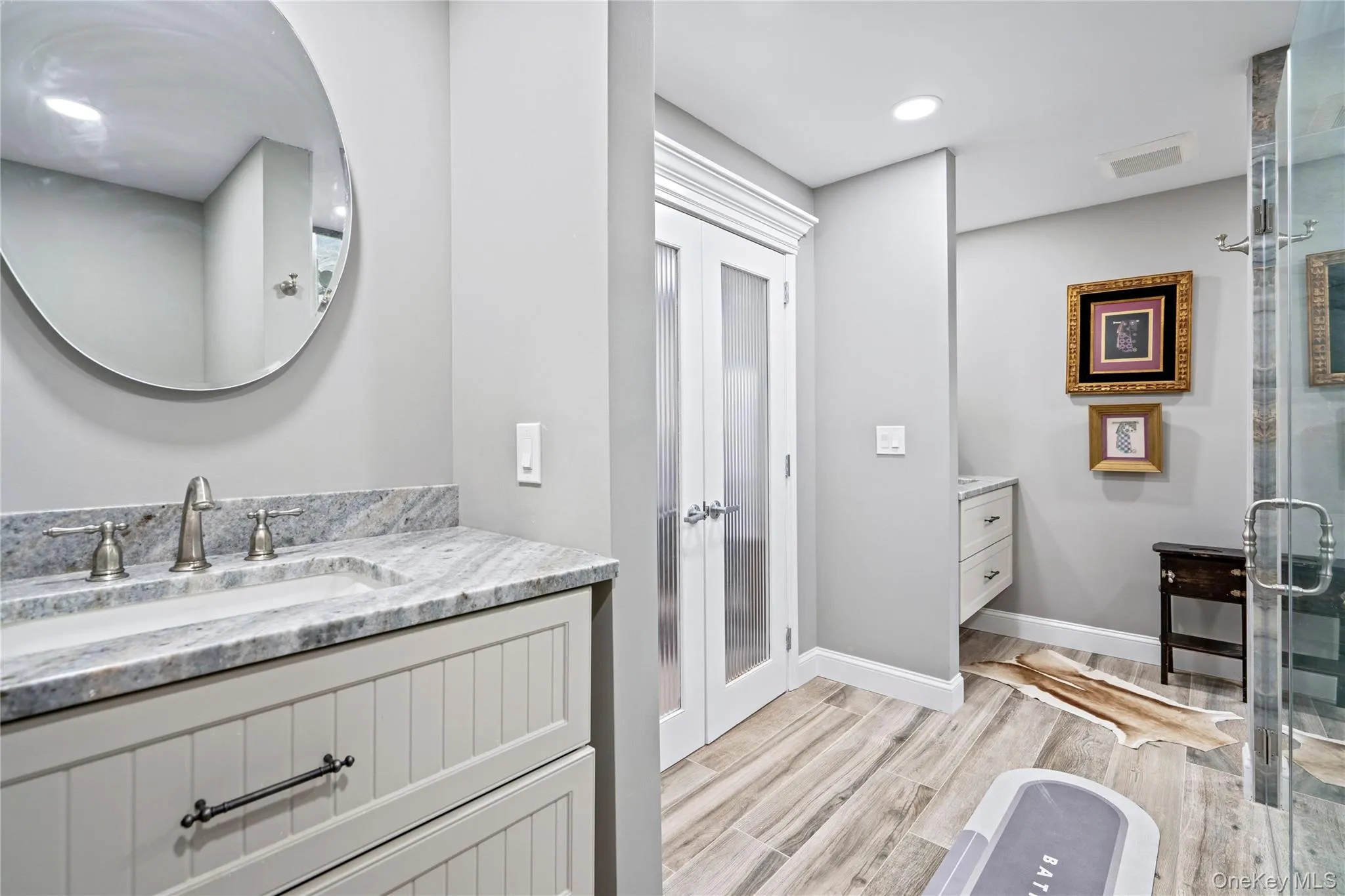 Bathroom featuring vanity, light wood-style floors, and a shower stall Bathroom featuring vanity, light wood-style floors, and a shower stall