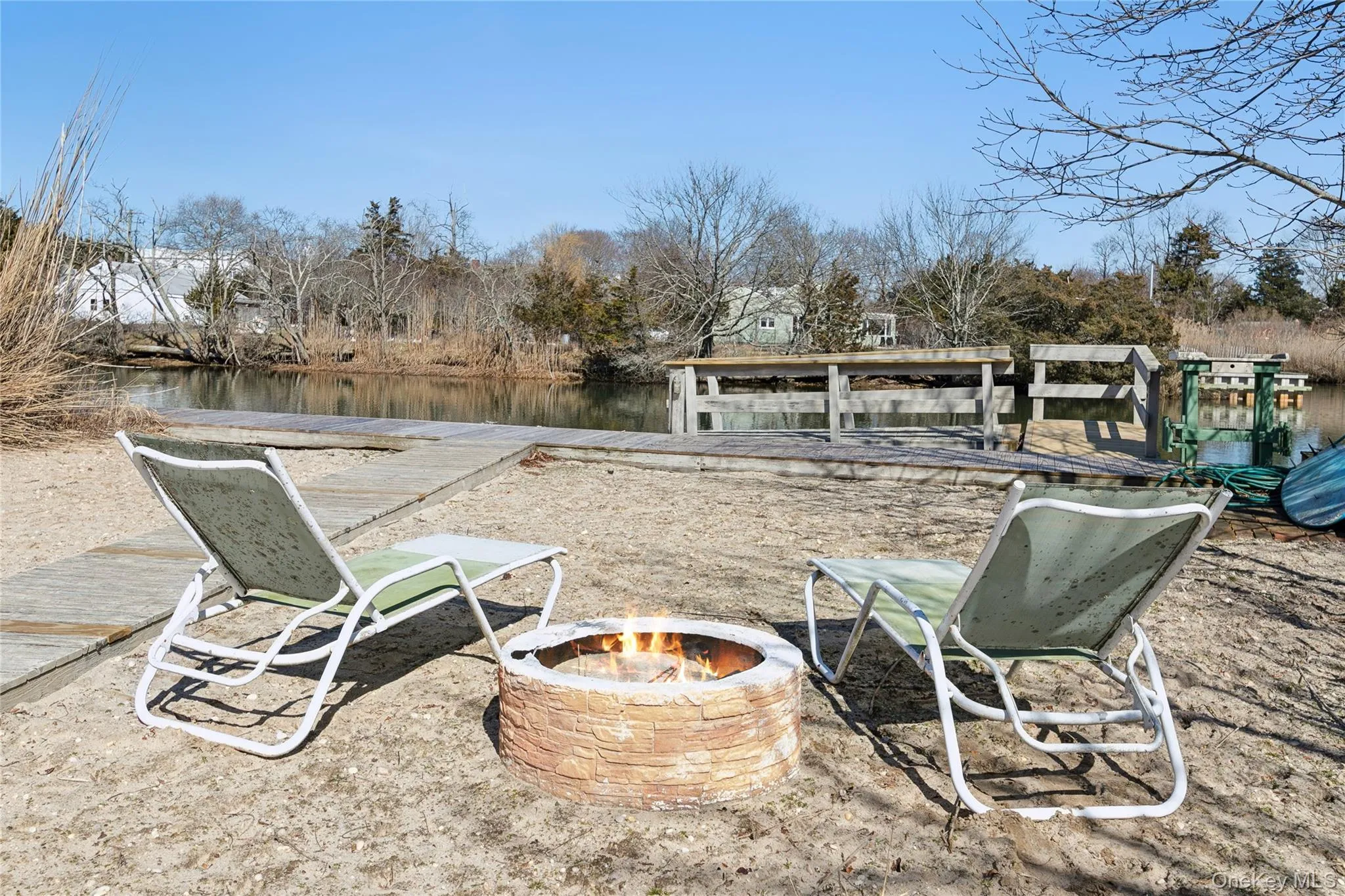 Lounge Chairs outside on the Beach with the Firepit facing the Canal