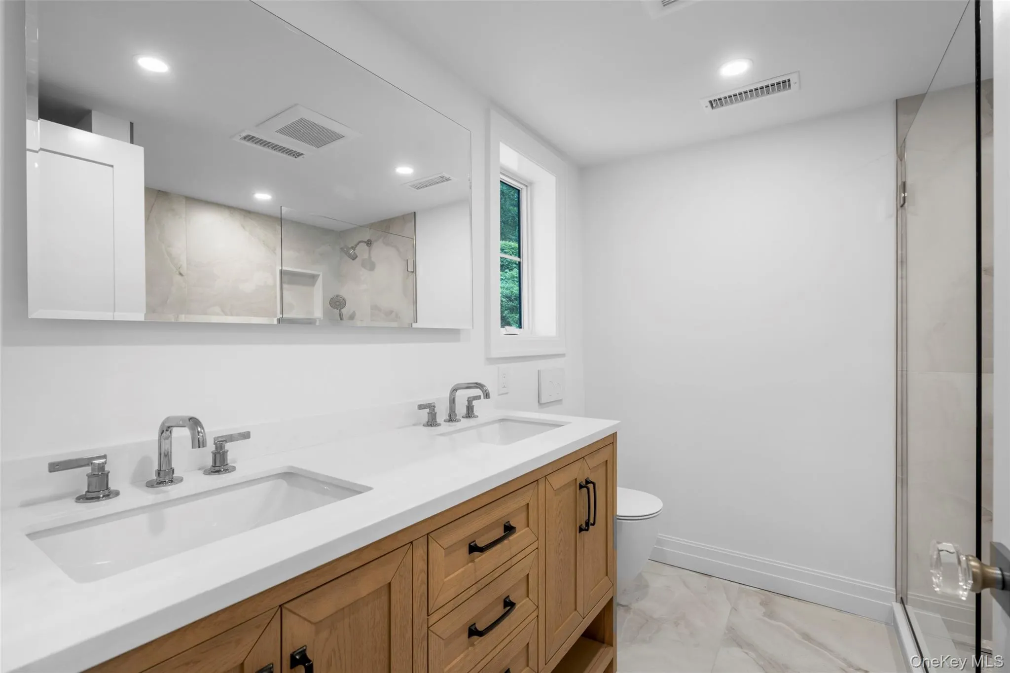 Full bathroom featuring marble look tiles, double vanity, a shower with shower door, and recessed lighting Full bathroom featuring marble look tiles, double vanity, a shower with shower door, and recessed lighting