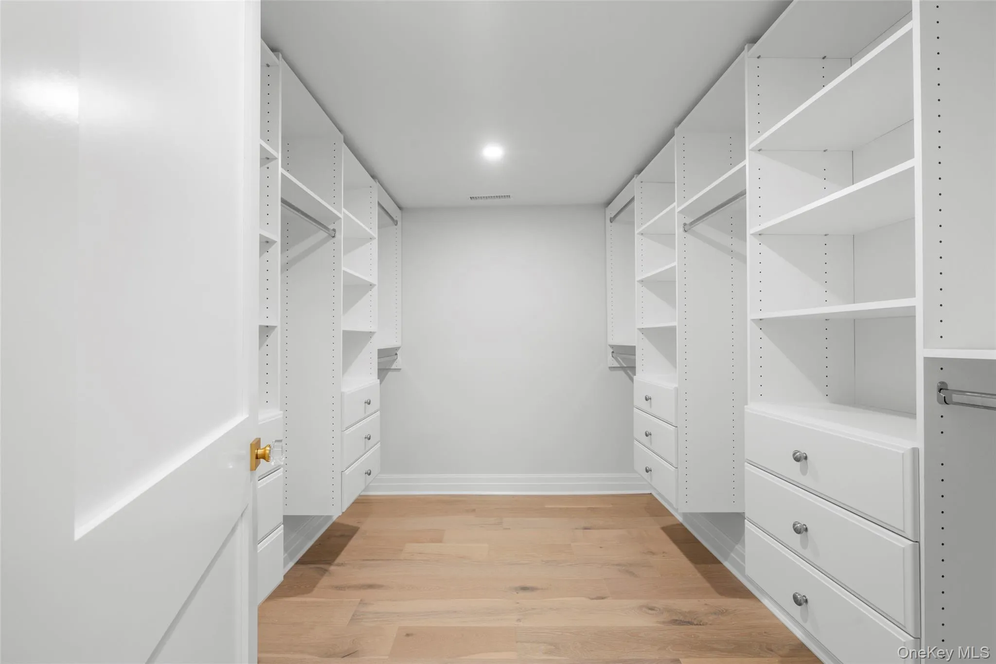 Spacious closet with light wood-type flooring Spacious closet with light wood-type flooring