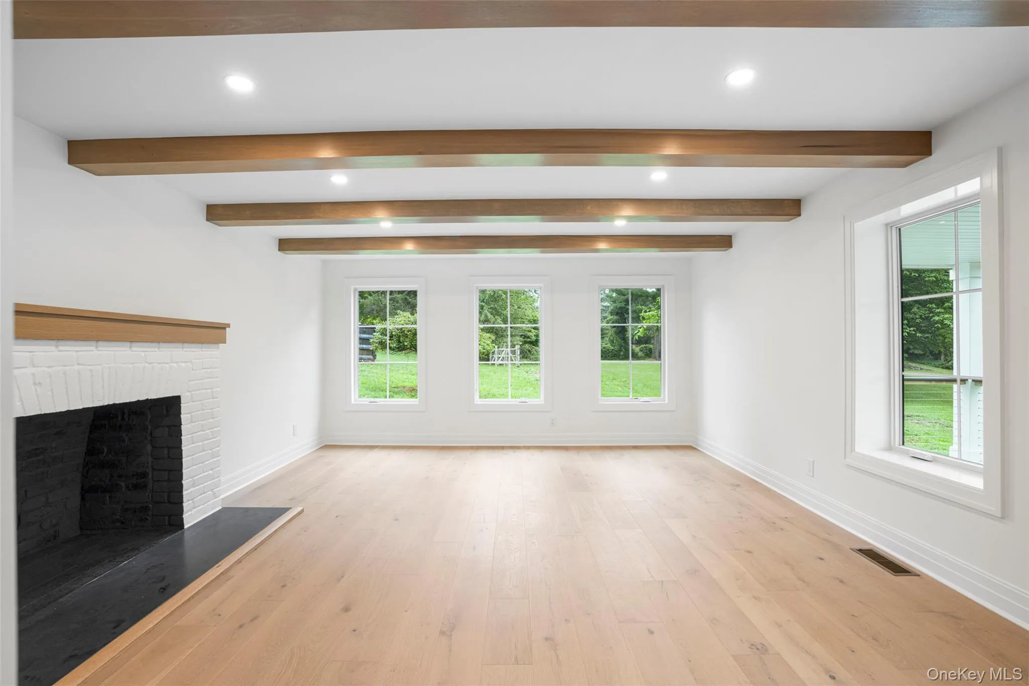 Unfurnished living room featuring healthy amount of natural light, a fireplace, recessed lighting, light wood-type flooring, and beam ceiling Unfurnished living room featuring healthy amount of natural light, a fireplace, recessed lighting, light wood-type flooring, and beam ceiling
