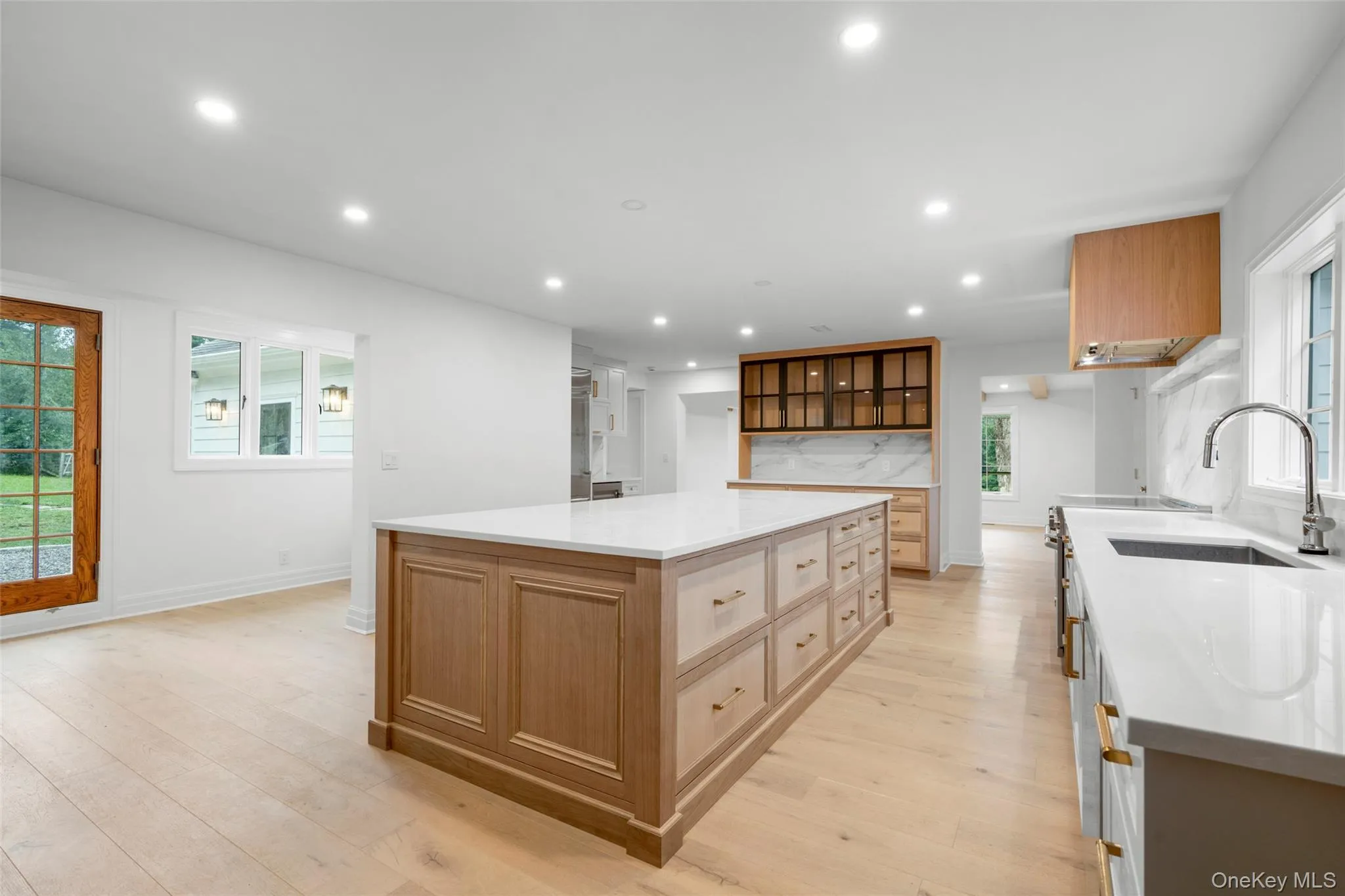 Kitchen featuring recessed lighting, light wood-style flooring, decorative backsplash, light countertops, and a large island Kitchen featuring recessed lighting, light wood-style flooring, decorative backsplash, light countertops, and a large island