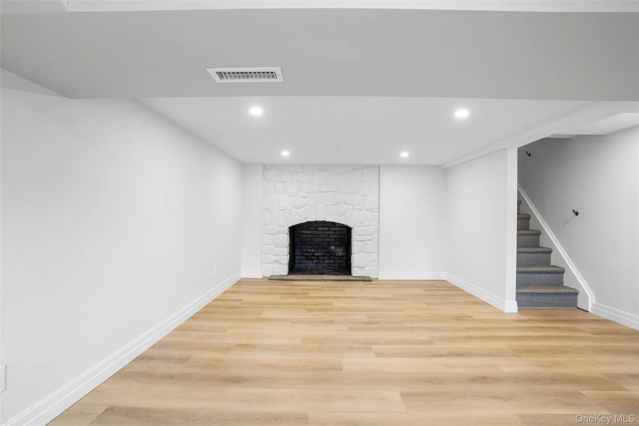 Basement playroom with recessed lighting, stairway, light wood-style floors, and a fireplace Basement playroom with recessed lighting, stairway, light wood-style floors, and a fireplace