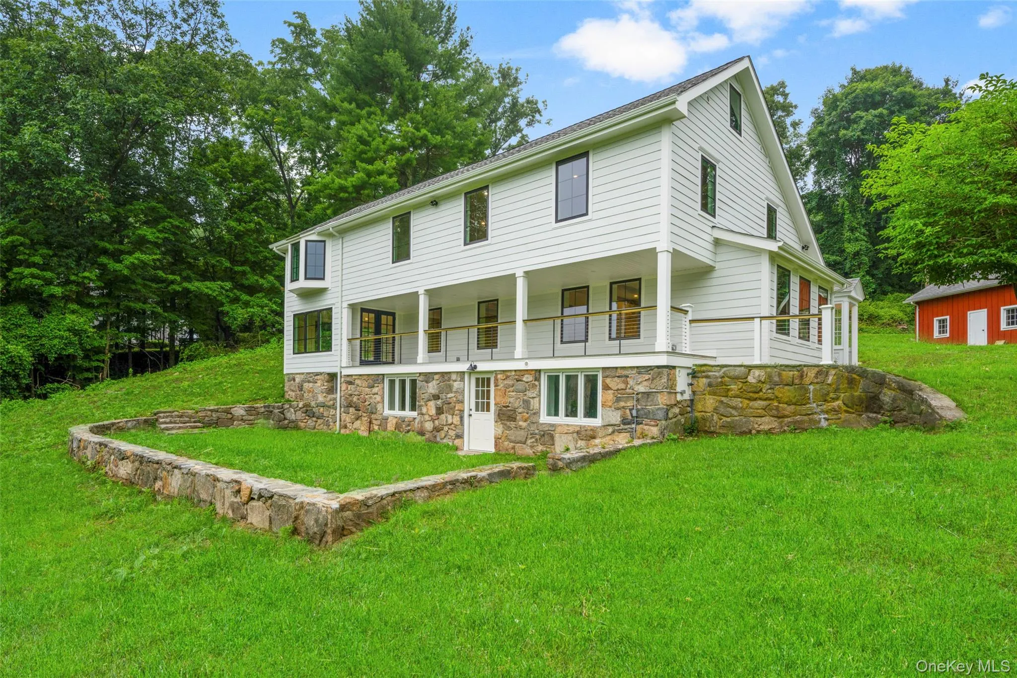 View of back facade featuring a covered porch overlooking the valley and stone features View of back facade featuring a covered porch overlooking the valley and stone features