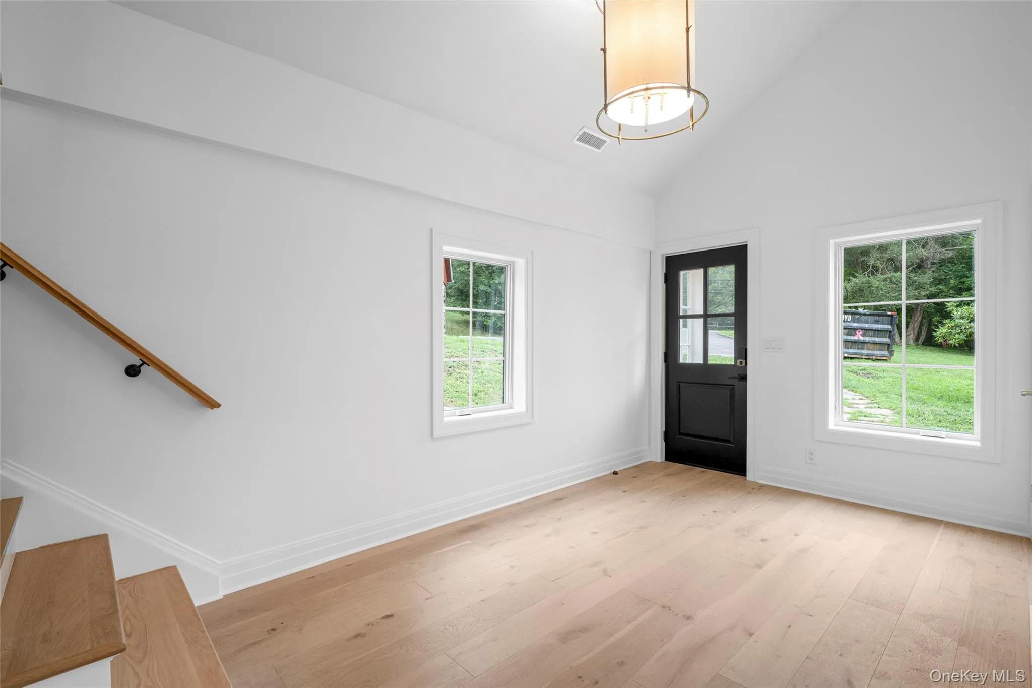Entrance foyer featuring light wood-type flooring, plenty of natural light, high vaulted ceiling, and stairs Entrance foyer featuring light wood-type flooring, plenty of natural light, high vaulted ceiling, and stairs
