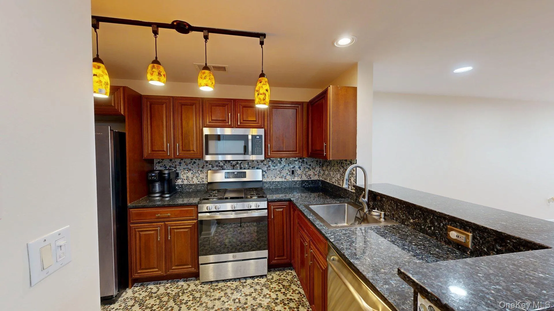 Kitchen featuring w/stainless steel appliances, rich wood cabinetry, beautiful tiled floors, backsplash and gorgeous countertops Kitchen featuring w/stainless steel appliances, rich wood cabinetry, beautiful tiled floors, backsplash and gorgeous countertops