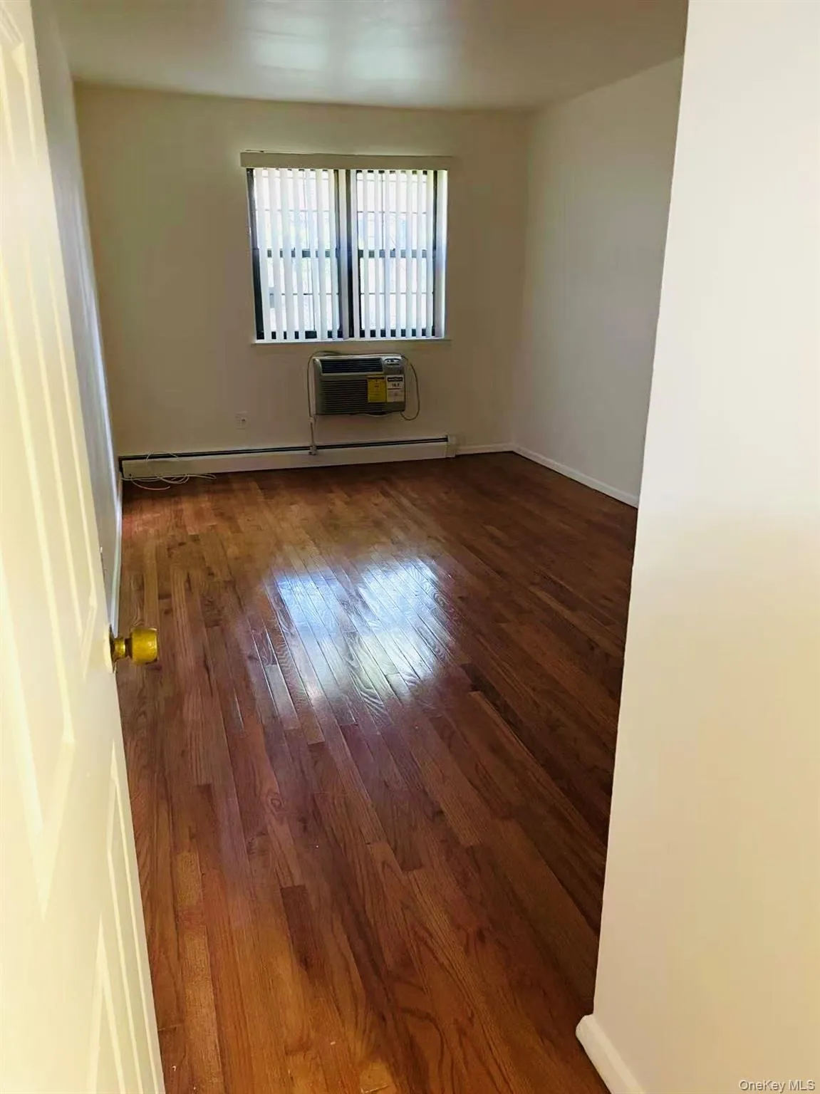 Empty room featuring hardwood / wood-style flooring and baseboard heating Empty room featuring hardwood / wood-style flooring and baseboard heating