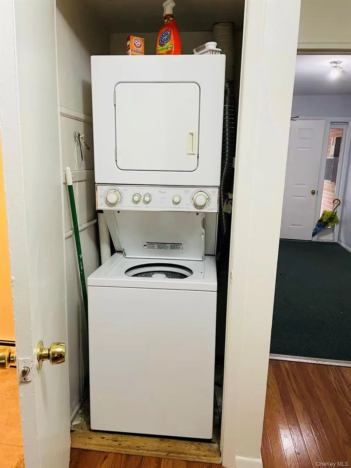 Laundry area featuring stacked washer / drying machine and hardwood / wood-style floors Laundry area featuring stacked washer / drying machine and hardwood / wood-style floors