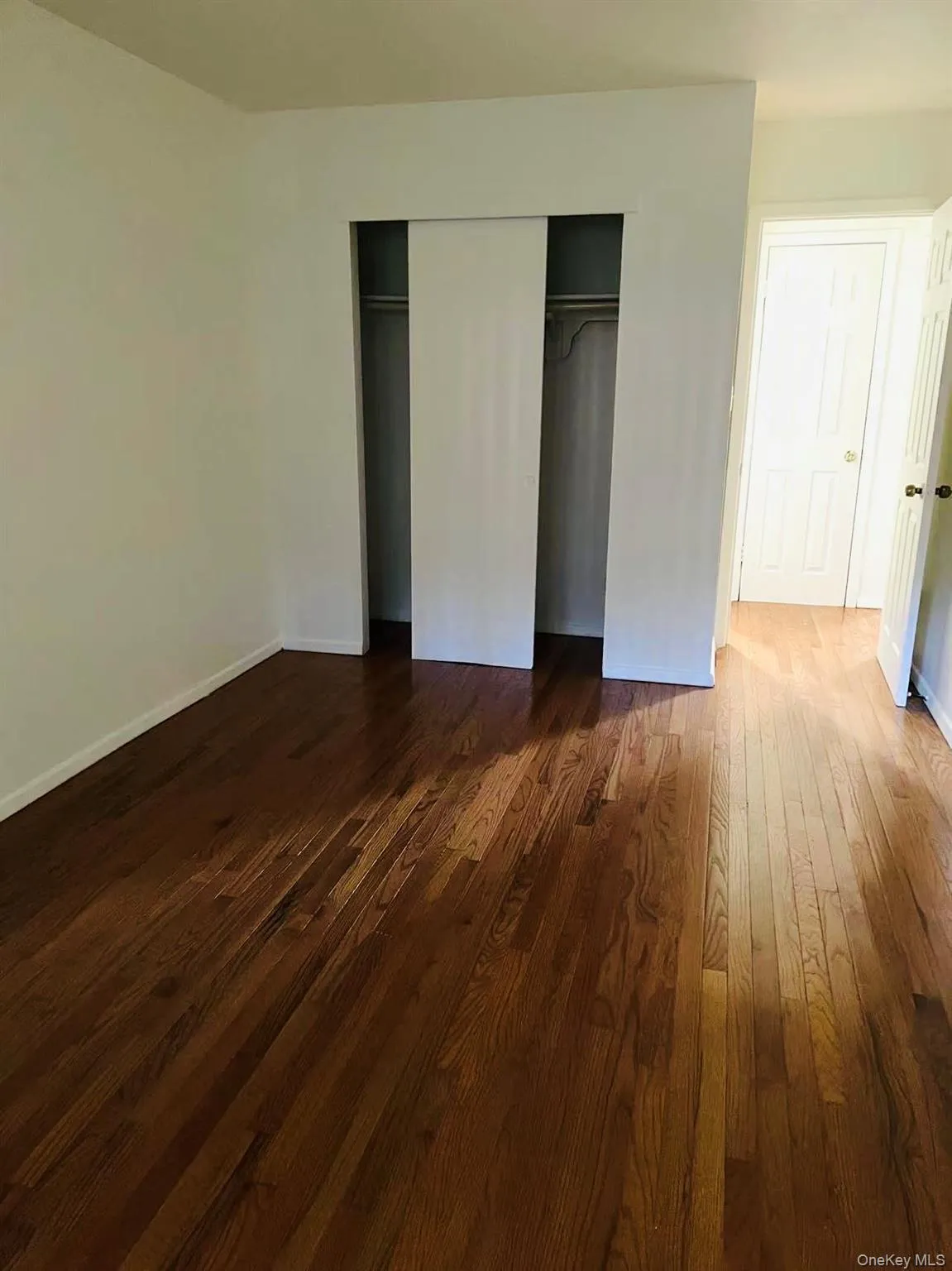 Unfurnished bedroom featuring dark wood finished floors and a closet Unfurnished bedroom featuring dark wood finished floors and a closet