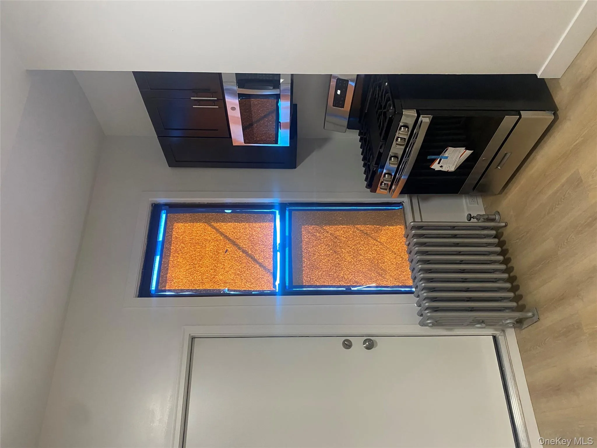 Kitchen with stainless steel appliances, radiator heating unit, and light wood-style floors Kitchen with stainless steel appliances, radiator heating unit, and light wood-style floors