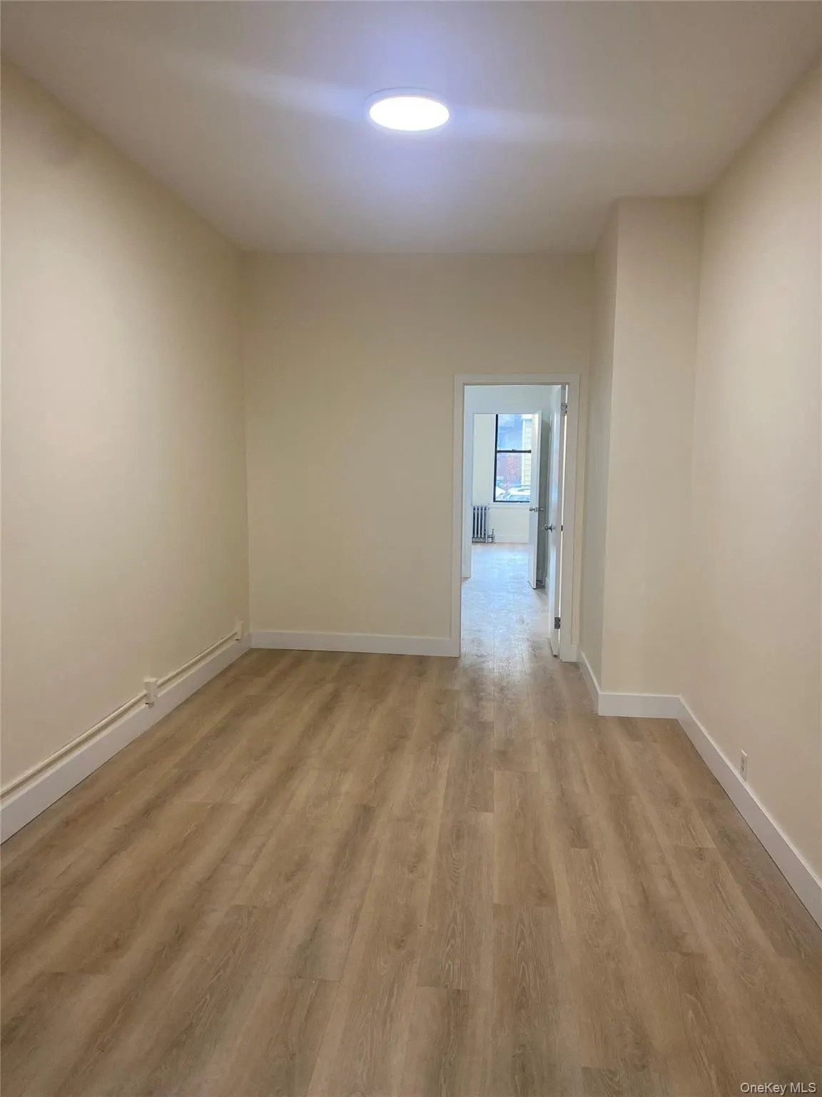 Spare room featuring light wood-style floors and baseboards Spare room featuring light wood-style floors and baseboards