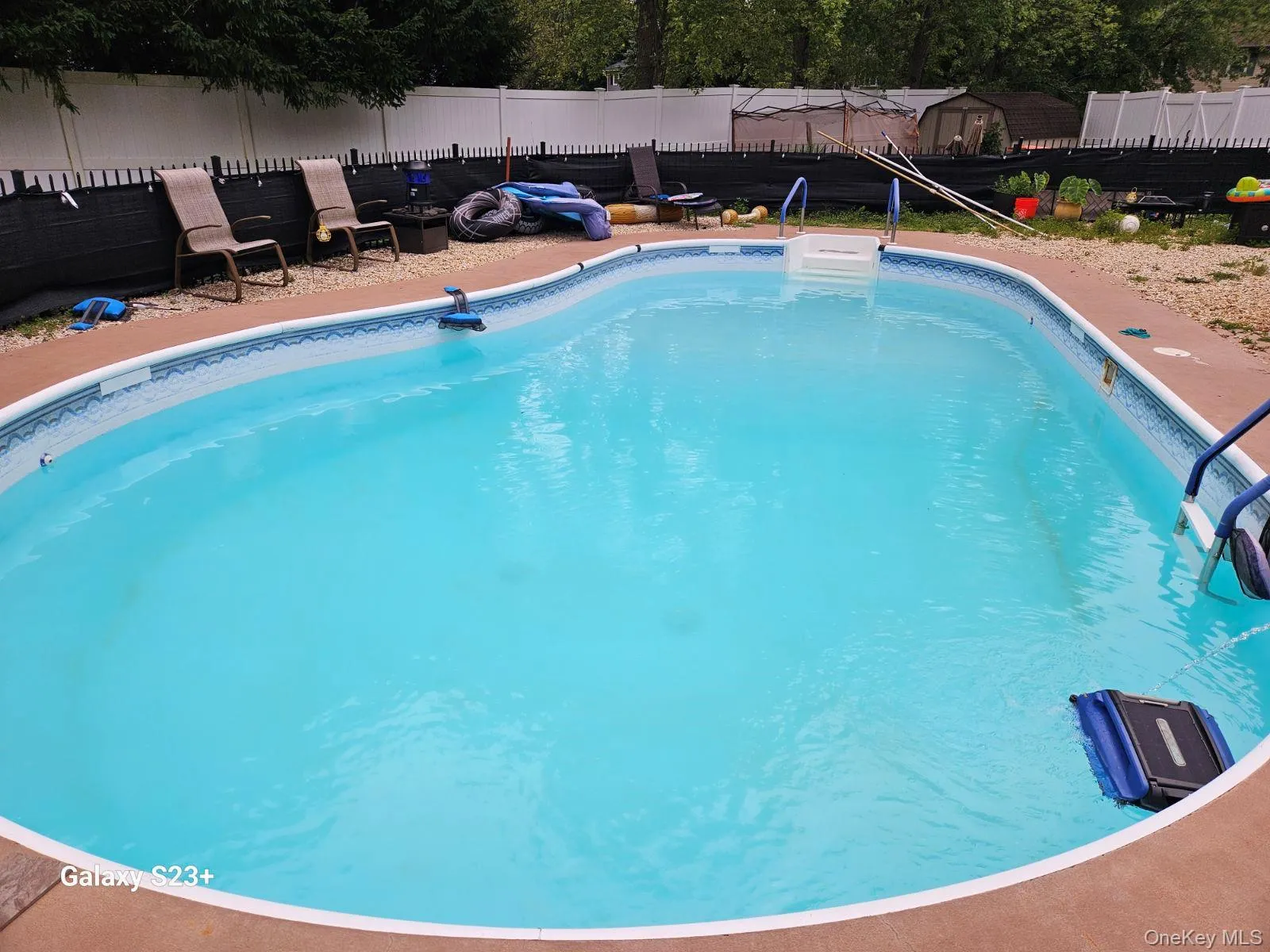 Kidney-shaped in-ground swimming pool featuring a patterned liner, white entry steps, and blue handrails Kidney-shaped in-ground swimming pool featuring a patterned liner, white entry steps, and blue handrails