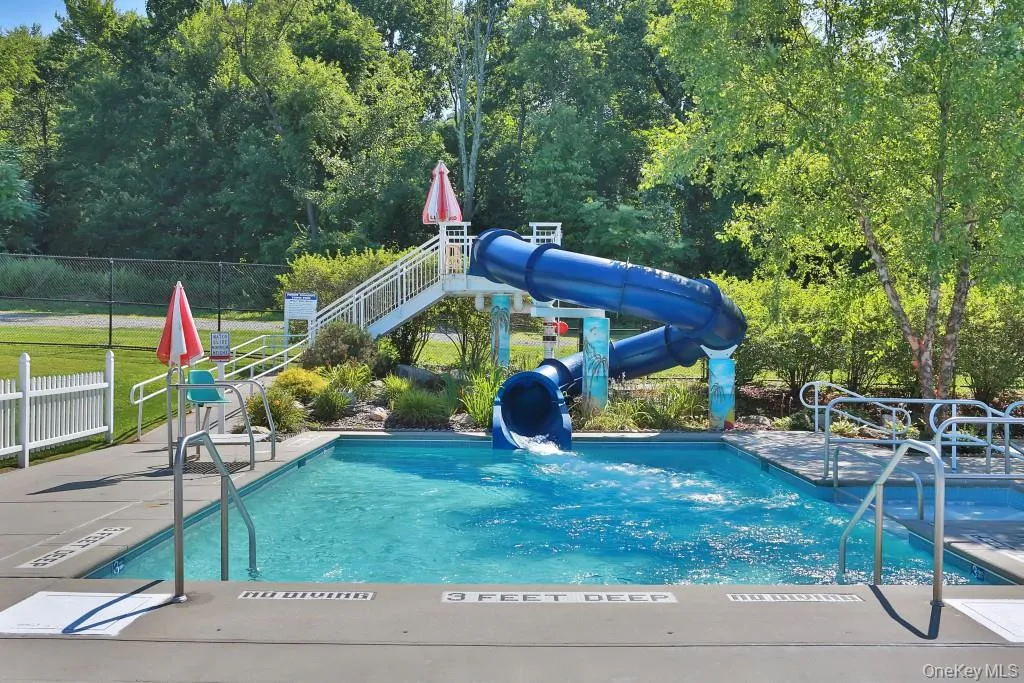 Pool features a water slide and a patio area Pool features a water slide and a patio area