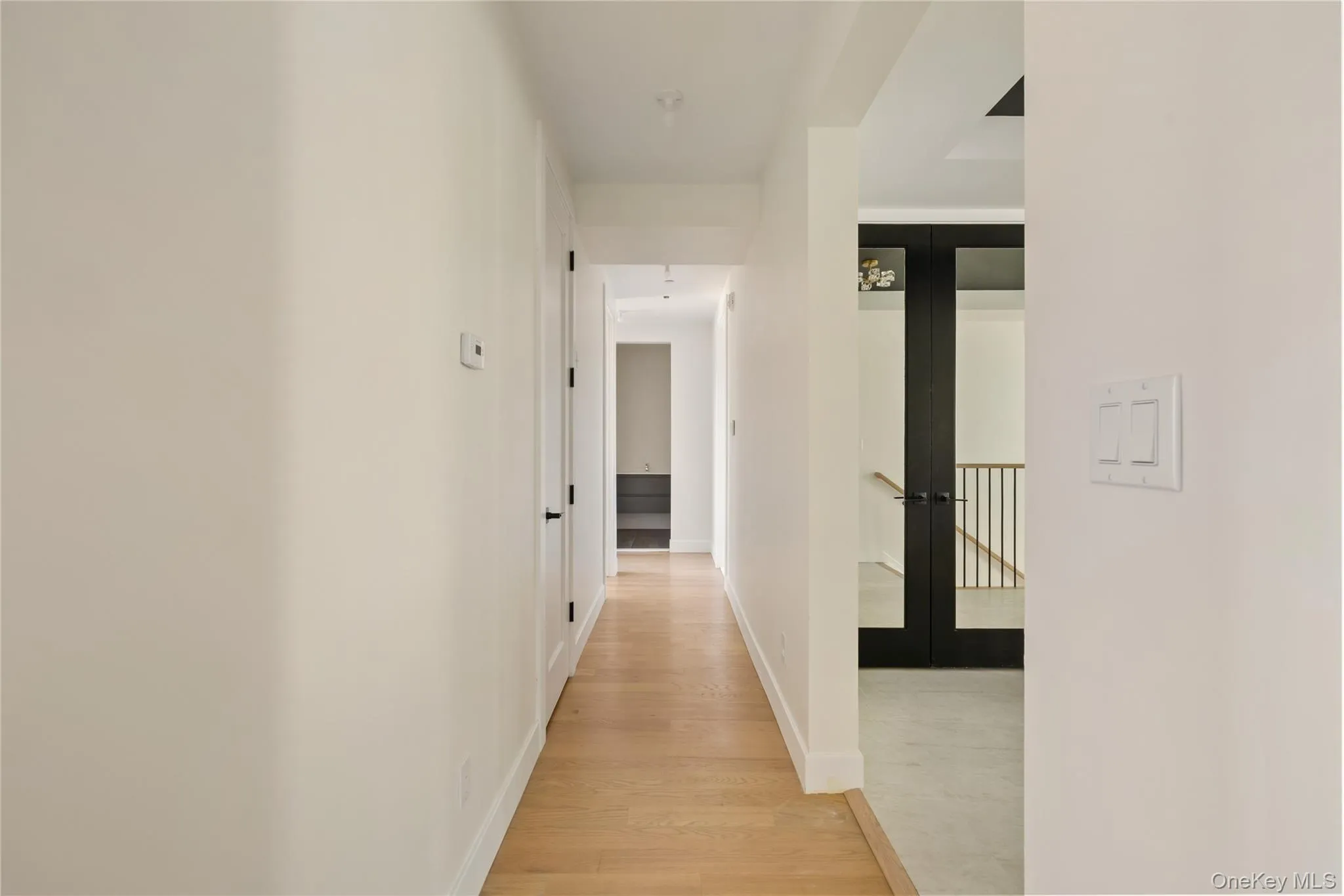 Hallway featuring light wood-type flooring and french doors Hallway featuring light wood-type flooring and french doors