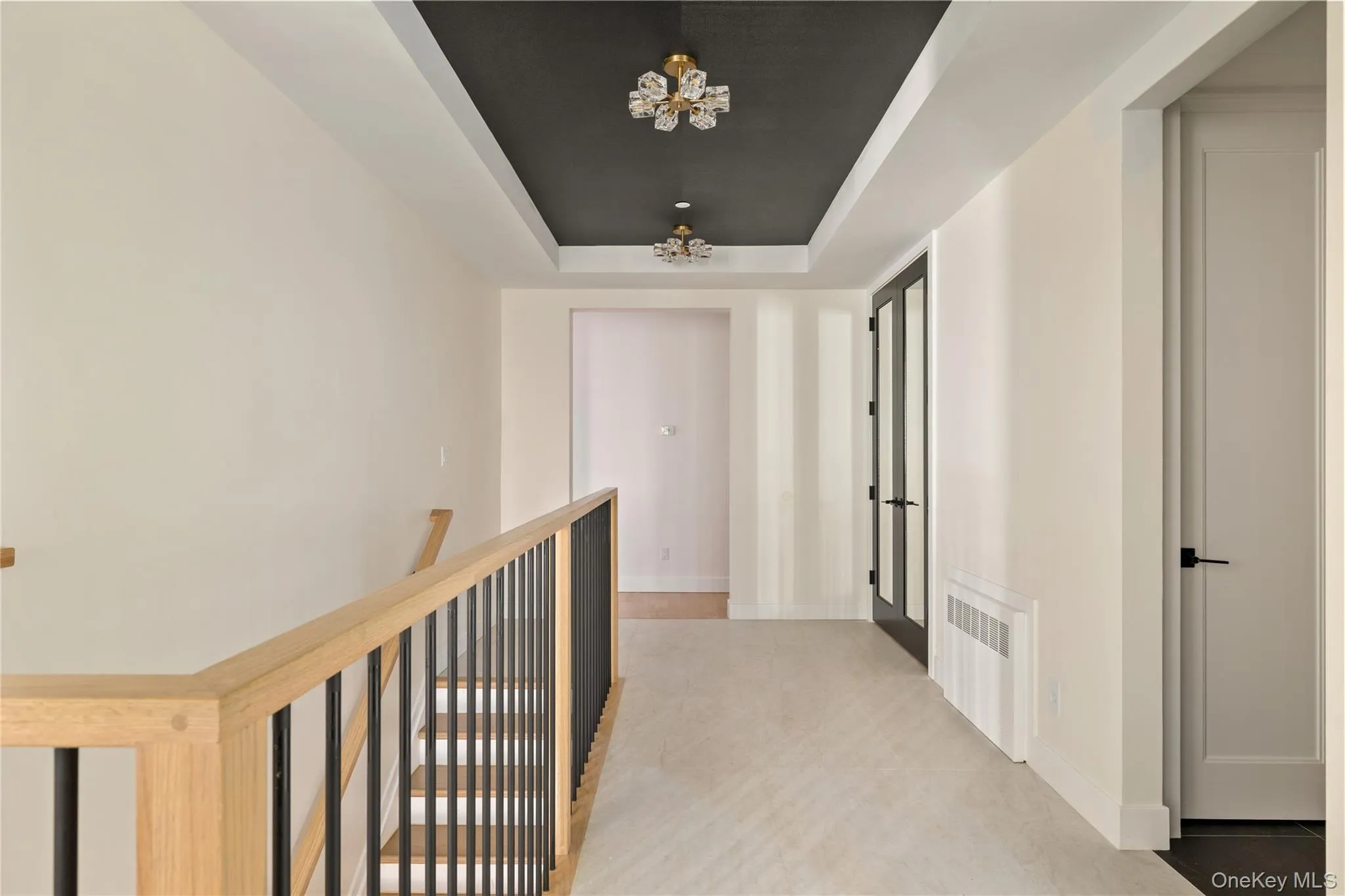 Hallway with a raised ceiling, a chandelier, and radiator Hallway with a raised ceiling, a chandelier, and radiator