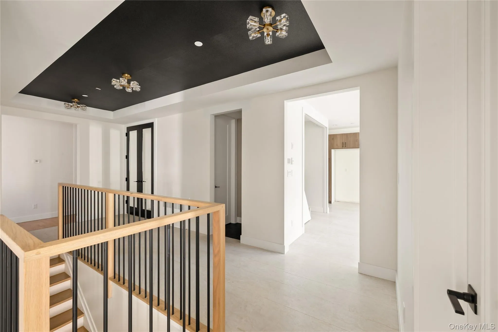 Corridor featuring a raised ceiling and an upstairs landing Corridor featuring a raised ceiling and an upstairs landing