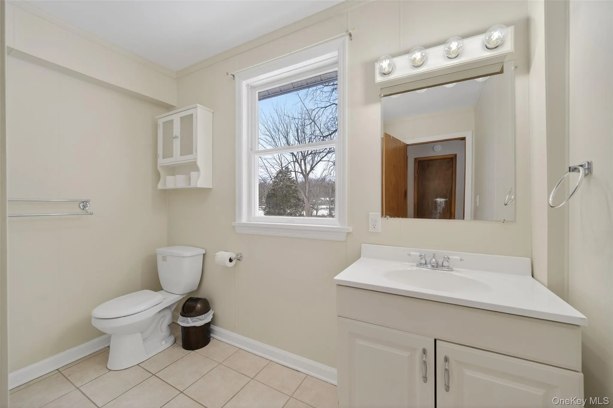 Bathroom with vanity, ornamental molding, and light tile patterned flooring Bathroom with vanity, ornamental molding, and light tile patterned flooring