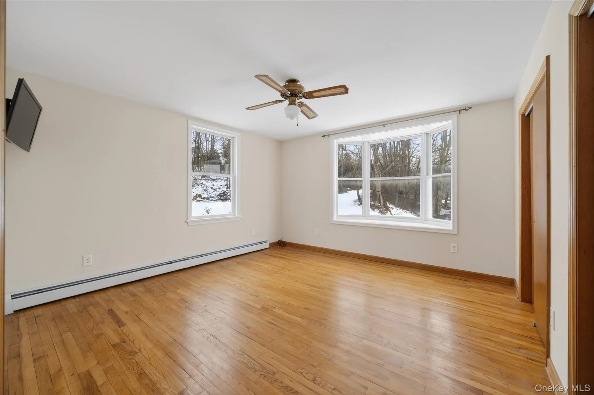 Unfurnished bedroom with baseboard heating, light wood-style floors, and a ceiling fan Unfurnished bedroom with baseboard heating, light wood-style floors, and a ceiling fan