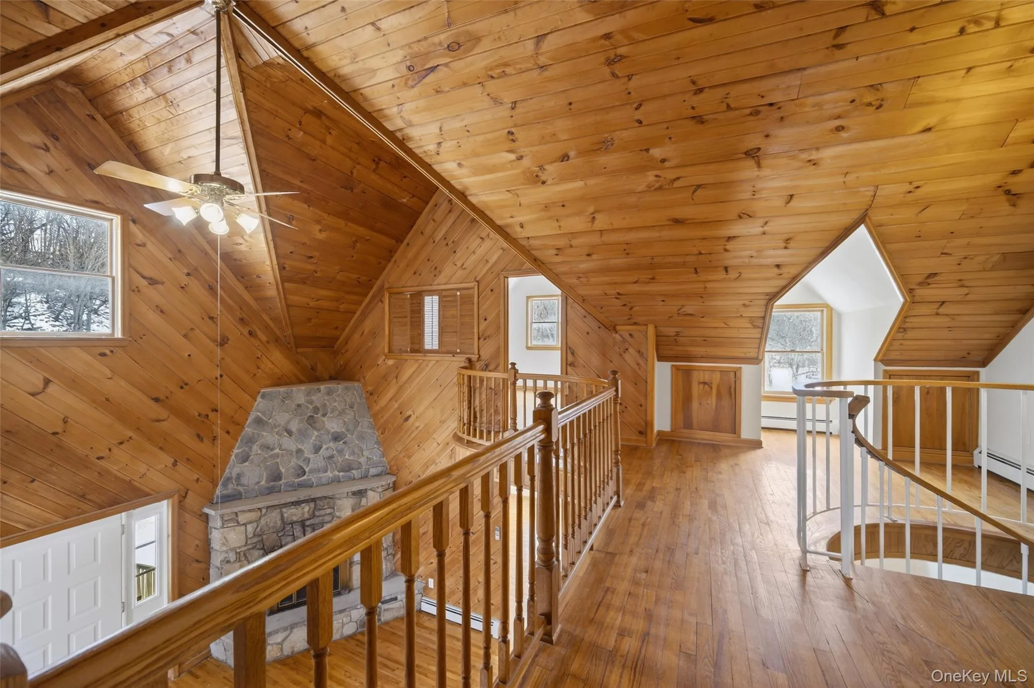 Hallway with an upstairs landing, hardwood / wood-style floors, a vaulted wood ceiling, a baseboard radiator, and wood walls Hallway with an upstairs landing, hardwood / wood-style floors, a vaulted wood ceiling, a baseboard radiator, and wood walls