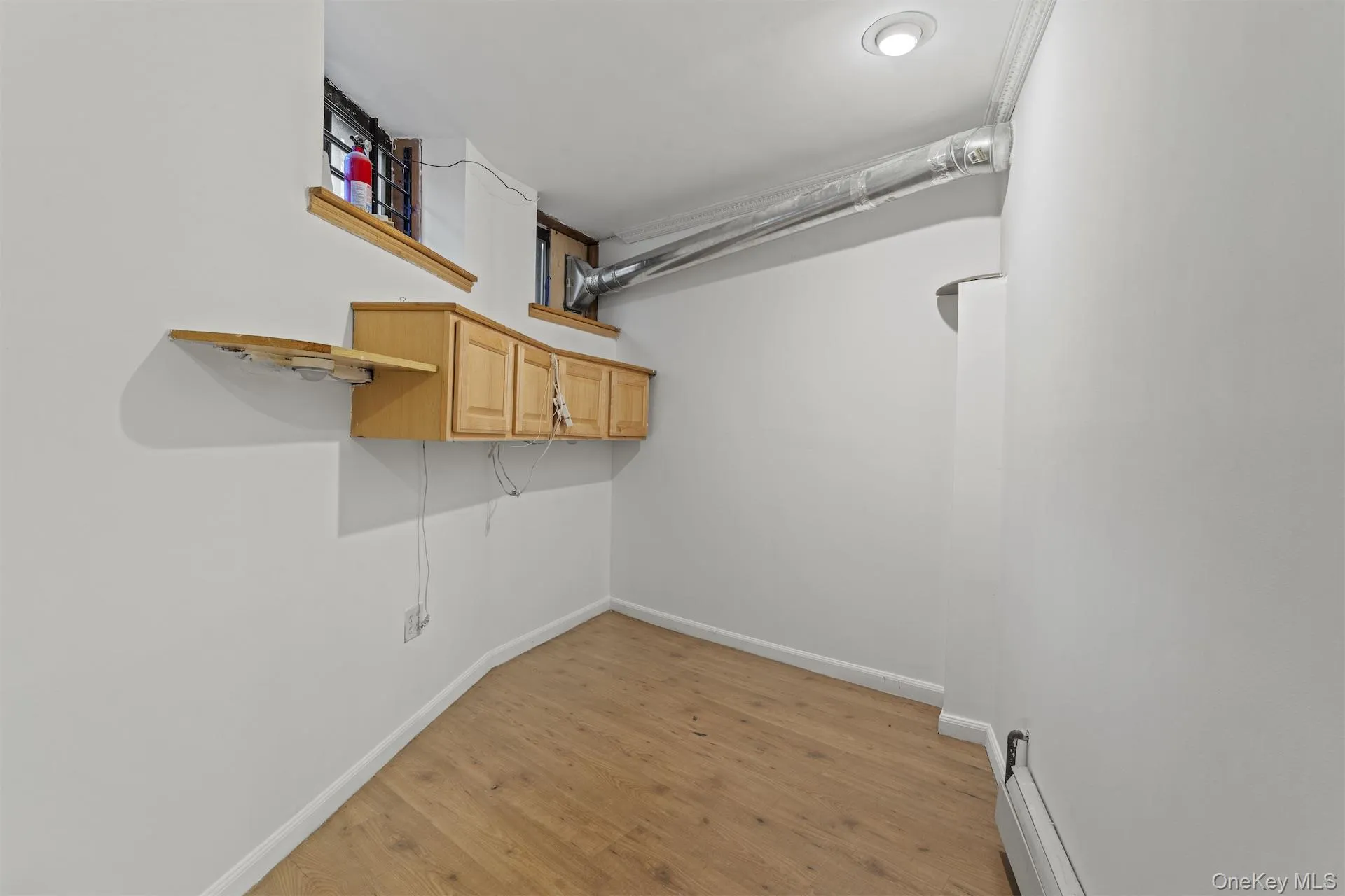 Laundry area featuring light wood-style flooring and a baseboard radiator Laundry area featuring light wood-style flooring and a baseboard radiator