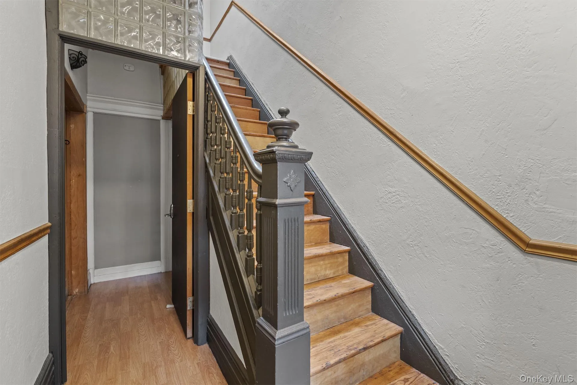 Staircase featuring a textured wall and wood finished floors Staircase featuring a textured wall and wood finished floors