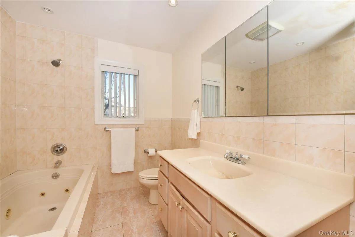 Bathroom with tile walls, vanity, light tile patterned floors, and a combined bath / shower with jetted tub Bathroom with tile walls, vanity, light tile patterned floors, and a combined bath / shower with jetted tub
