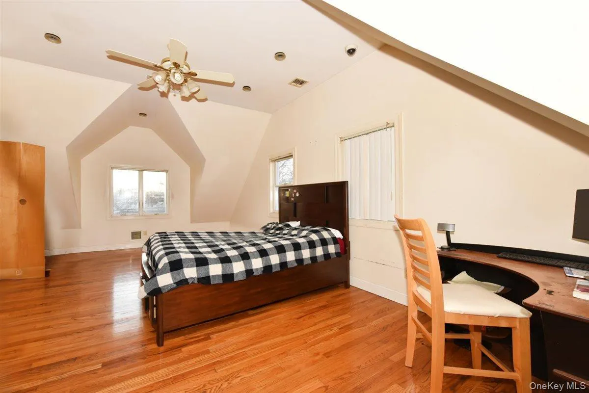 Bedroom featuring multiple windows, light wood-type flooring, lofted ceiling, and a ceiling fan Bedroom featuring multiple windows, light wood-type flooring, lofted ceiling, and a ceiling fan