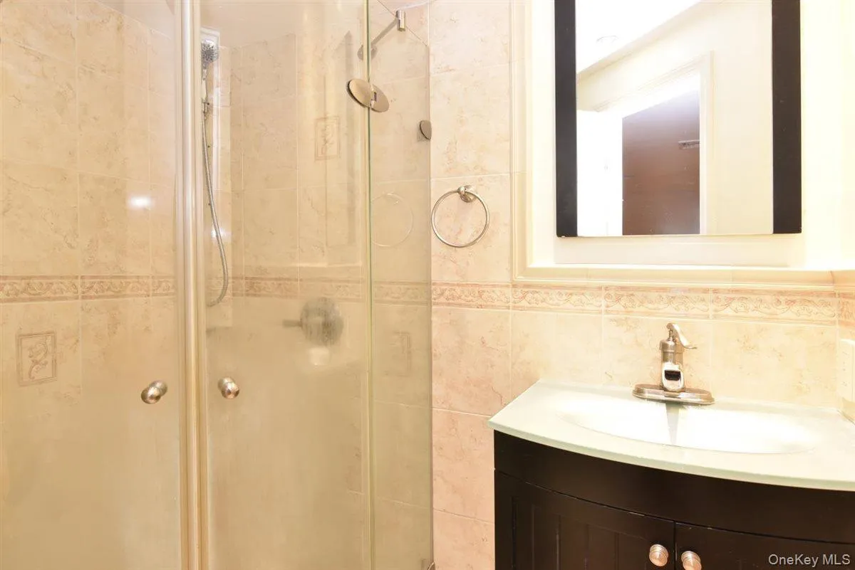 Full bath featuring vanity, a stall shower, and tile walls Full bath featuring vanity, a stall shower, and tile walls