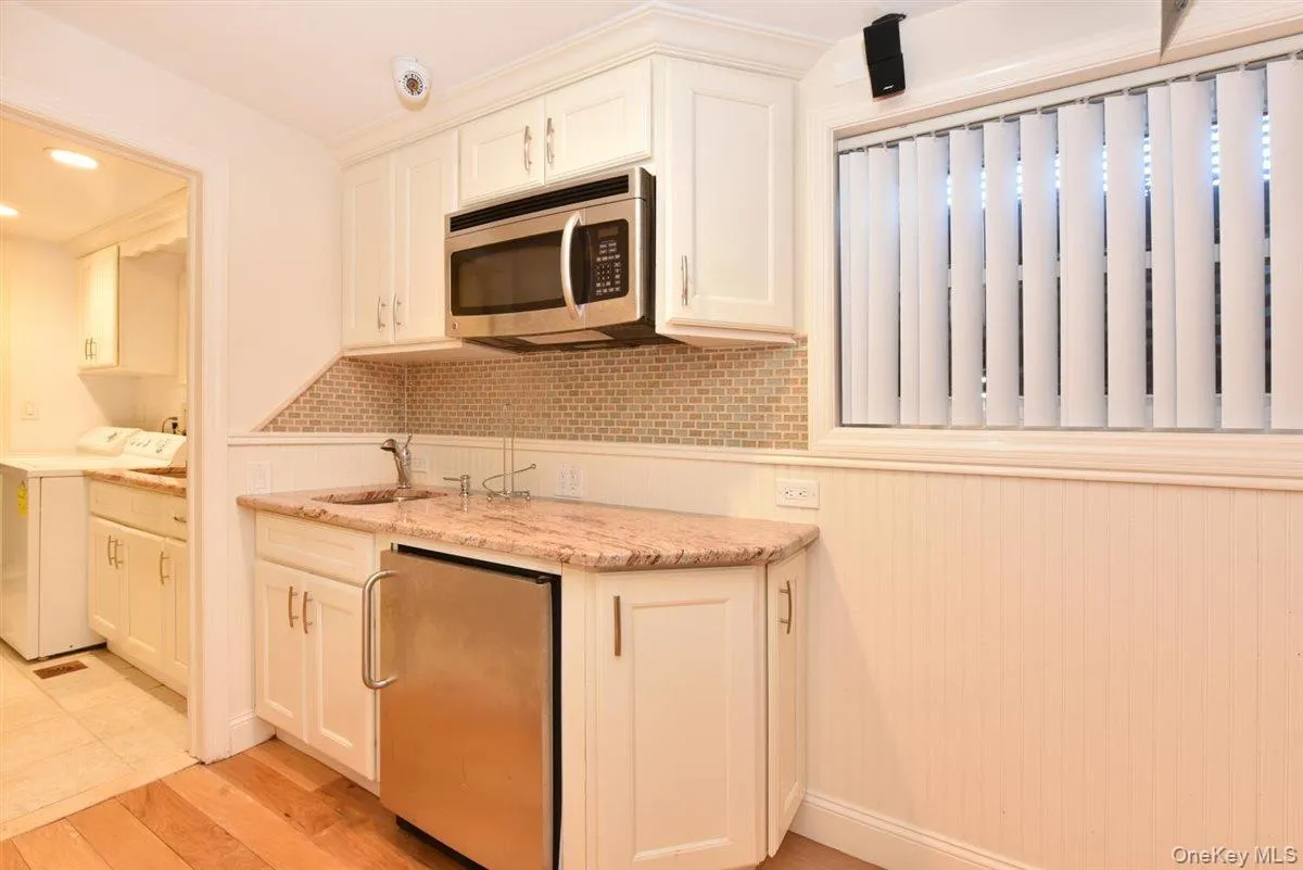 Kitchen with stainless steel appliances, white cabinets, light stone counters, light wood finished floors, and tasteful backsplash Kitchen with stainless steel appliances, white cabinets, light stone counters, light wood finished floors, and tasteful backsplash