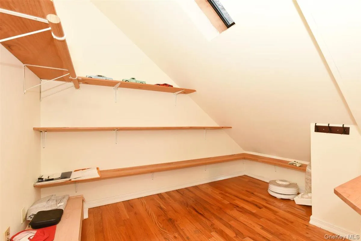 Spacious closet featuring light wood-style floors, lofted ceiling, and a skylight Spacious closet featuring light wood-style floors, lofted ceiling, and a skylight