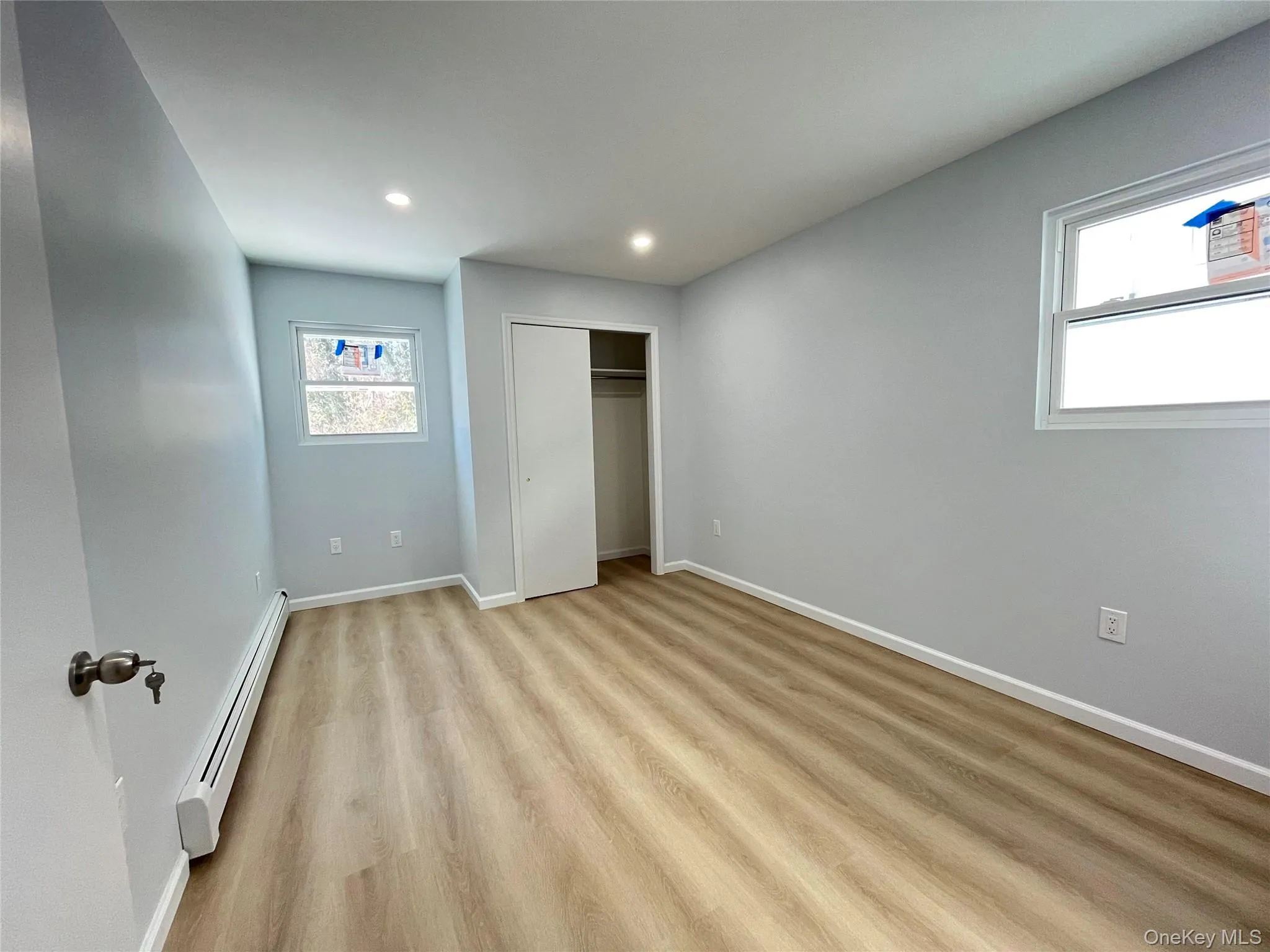 Bedroom with a baseboard radiator, light wood-style floors, recessed lighting, and a closet Bedroom with a baseboard radiator, light wood-style floors, recessed lighting, and a closet