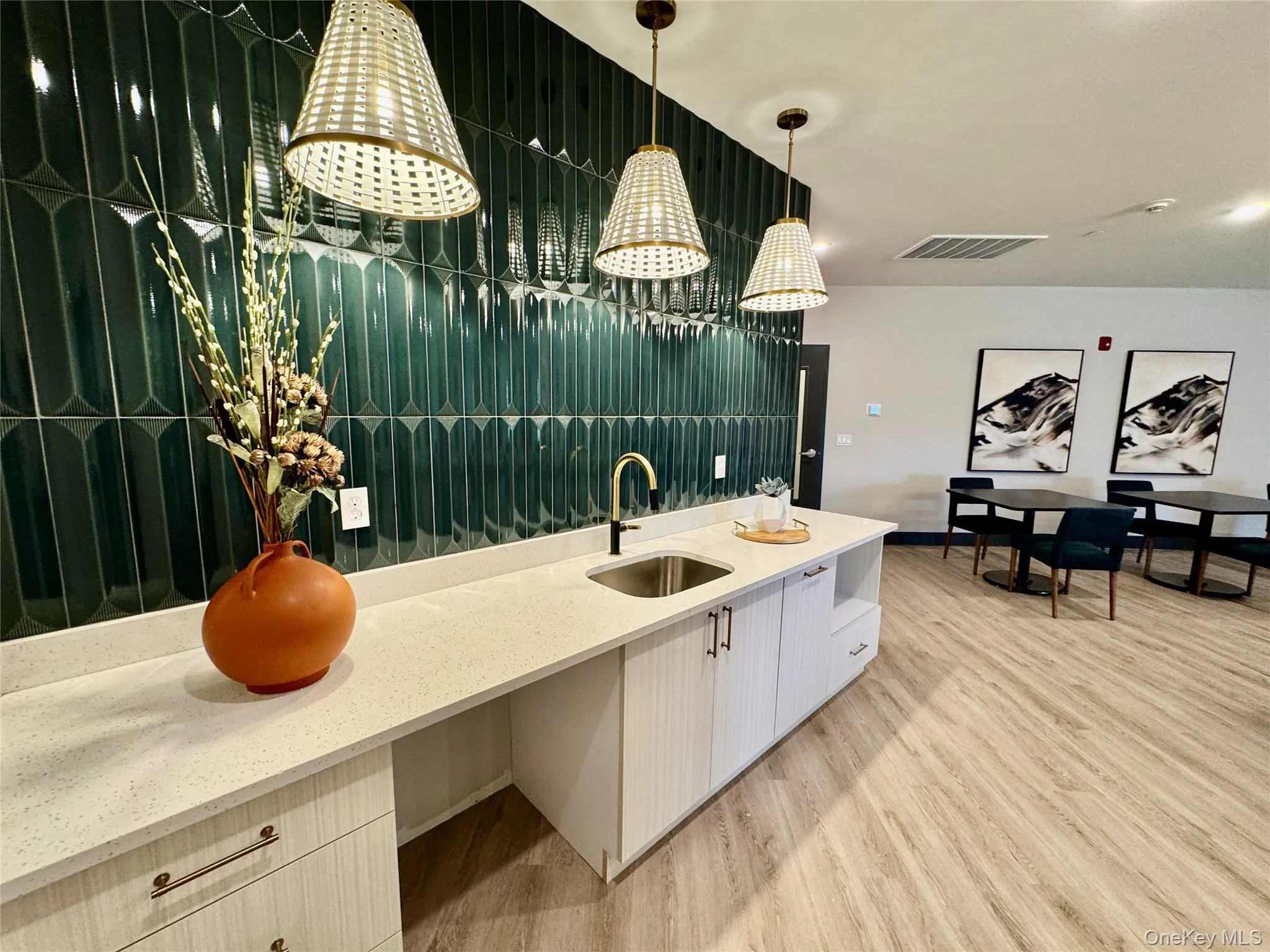 Kitchen featuring sink, light stone counters, light wood-type flooring, and hanging light fixtures Kitchen featuring sink, light stone counters, light wood-type flooring, and hanging light fixtures