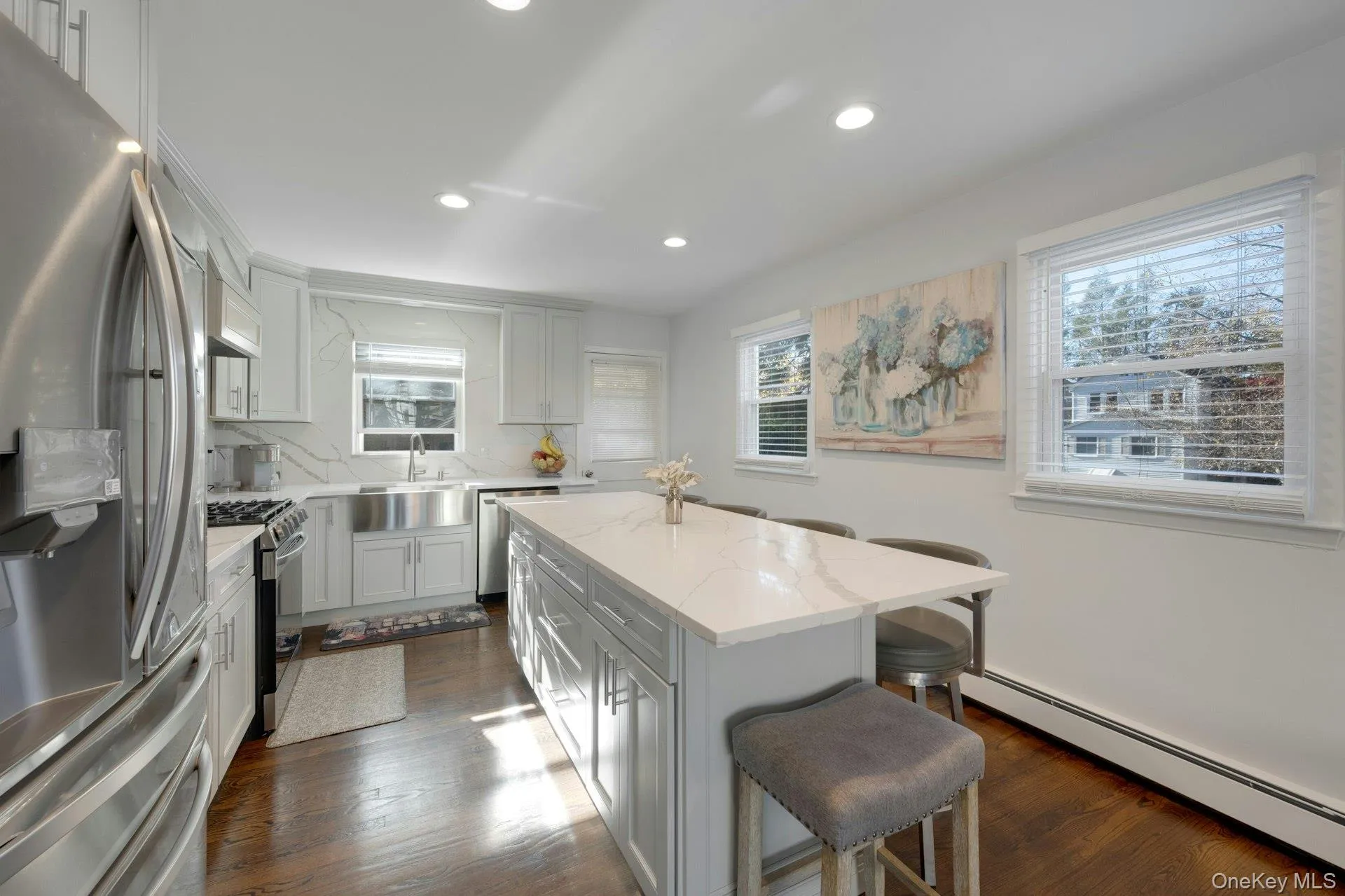 Kitchen with a healthy amount of sunlight, a center island, stainless steel appliances, and a baseboard heating unit Kitchen with a healthy amount of sunlight, a center island, stainless steel appliances, and a baseboard heating unit